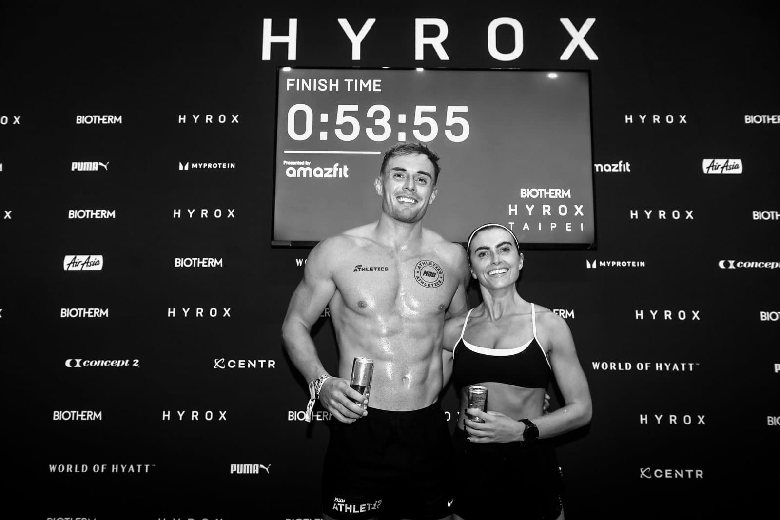 James and Megan at the Hyrox Taipei finish board showing a time of 0:53:55